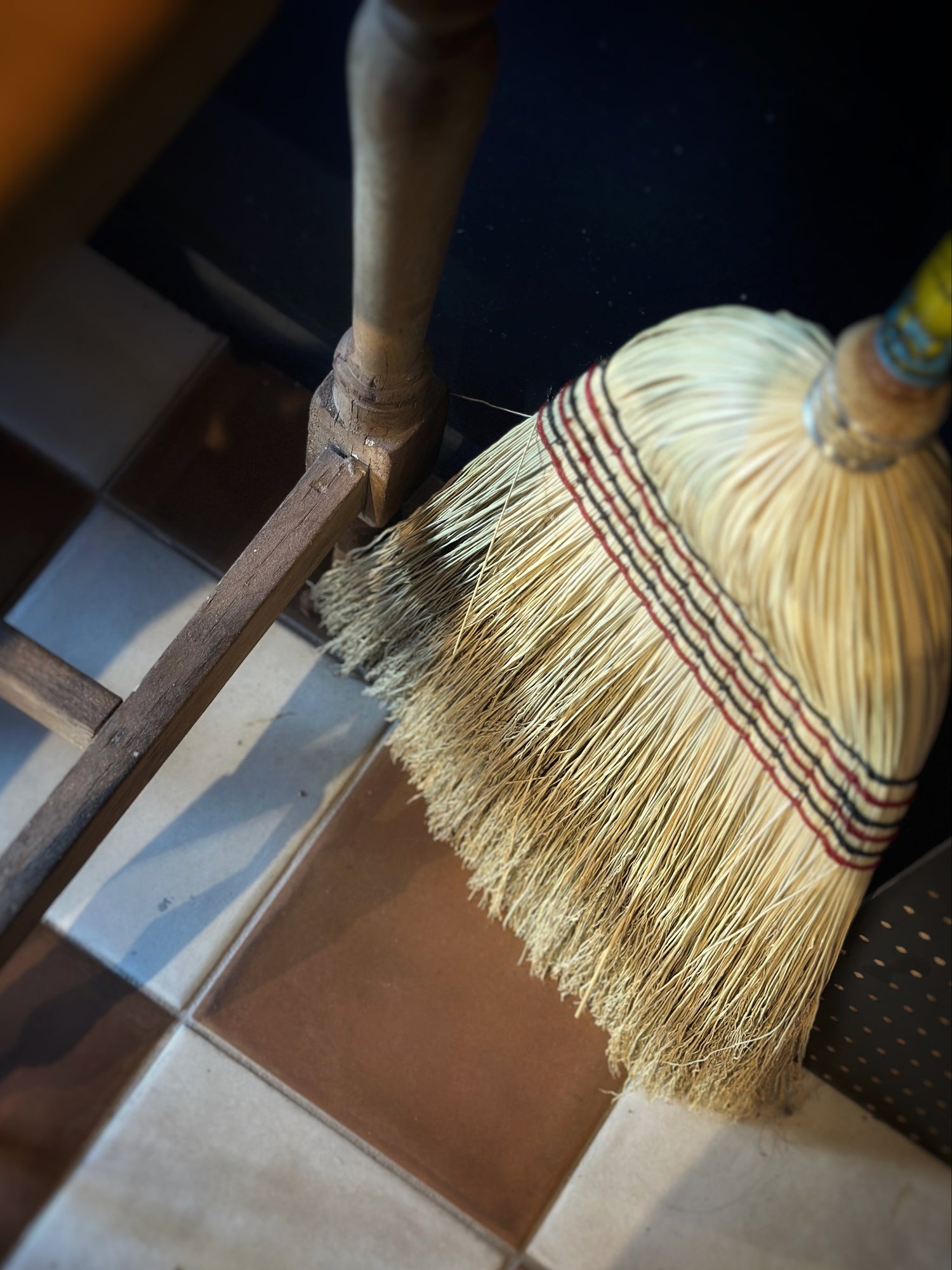 Broom with a striped handle on a tiled floor